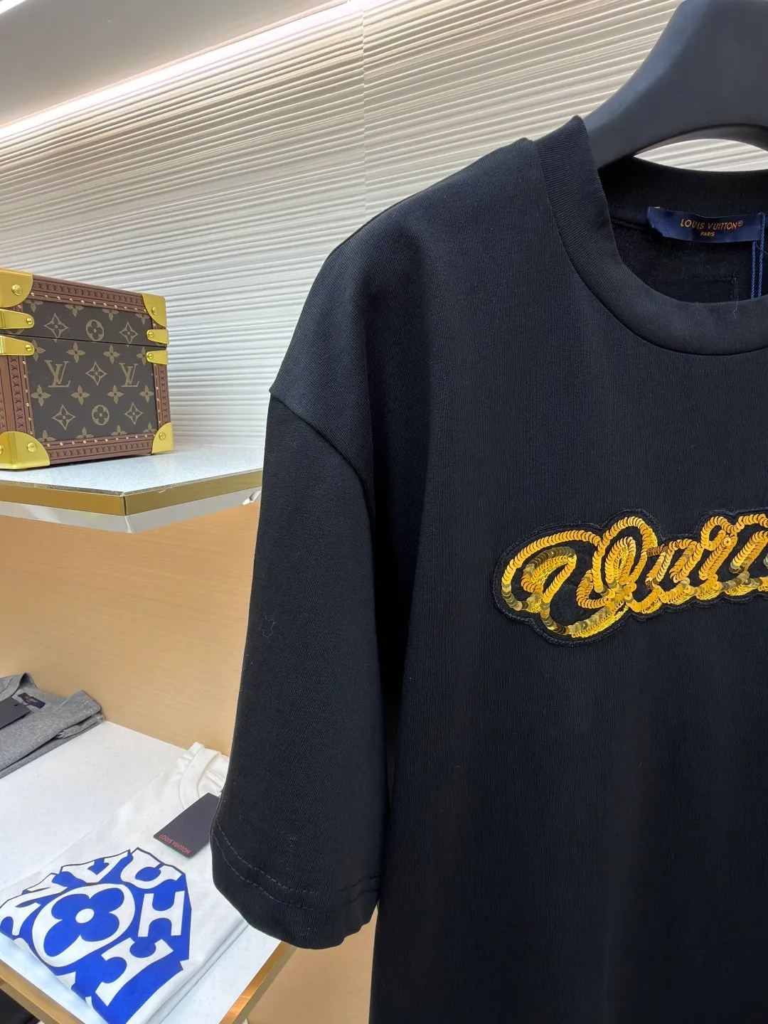 LOUIS VUITTON cotton round neck embroidered Vuitton signature logo short sleeves ●Original version: purchased and developed for 12300 ●Item number: 1682273-A10 ●Fabric: cotton fabric ●Technology: embroidery production ●Color: black ●Version: fitted version ●Weight: about 295 grams ●Size: S-M-L-XL ●Description: This white short-sleeved T-shirt is made of high-count combed cotton fabric and has been treated with pre-washing technology. It has a soft and skin-friendly touch and is not easy to deform. The silhouette of the shirt is a loose shoulder design, which meets the needs of modern casual wear. The core decoration area on the chest uses hand-beading and bronzing technology, and uses metallic gold sequins and embroidery threads intertwined to outline a three-dimensional letter pattern. The sequins are layered and inlaid, and each one is manually positioned and fixed by craftsmen to ensure a regular texture and uniform gloss. The edges of the letters are sewn with matte silk thread to form a visual contrast between gold and matte, while reinforcing the decorative structure to avoid falling off during wear. The neckline uses double-needle hemming technology and is matched with ribbed cuffs of the same fabric. It is durable and fits the neck. The overall craftsmanship combines handicraftsmanship with modern clothing technology, and the details show exquisite texture. The overall wiring is straight and delicate, the fabric is comfortable and soft, and the color is consistent without color difference. It can be matched with the same style to create a fashionable look and control various occasions. Customized accessories, complete with three standards, same style for men and women!